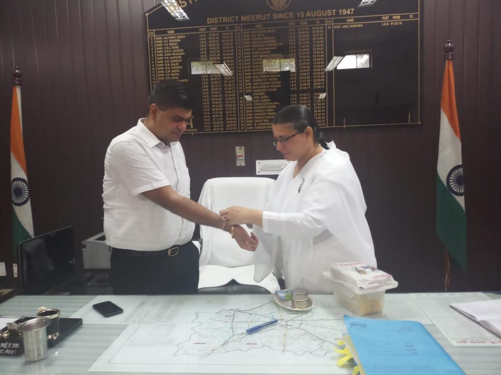 BK Sunita Bahen Tying Rakhi to D.M. ANIL DINGRA, Meerut